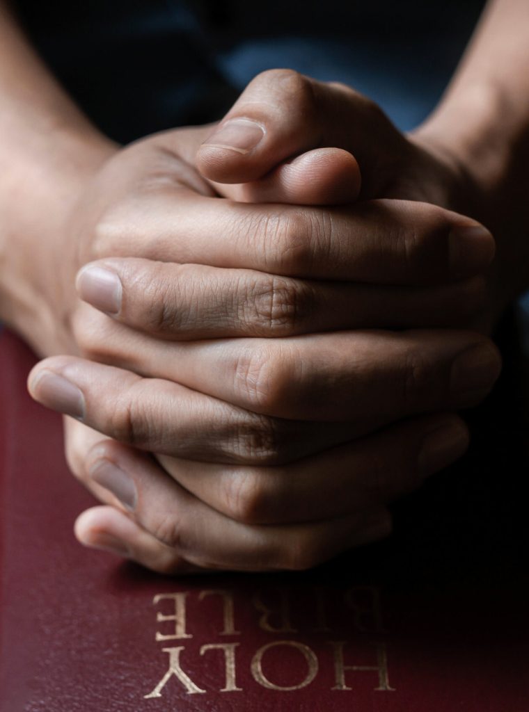 Hands together in prayer to God along with the bible In the Christian concept of faith, spirituality and religion, men pray in the Bible. prayer bible