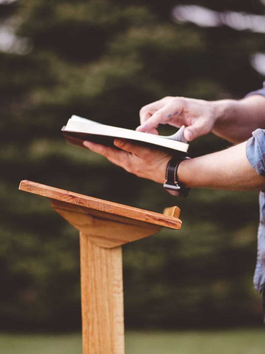 A shallow focus shot of a male near a speech stand with an opened book